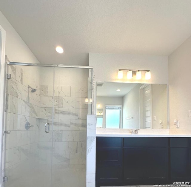 bathroom featuring a shower with door, vanity, and a textured ceiling