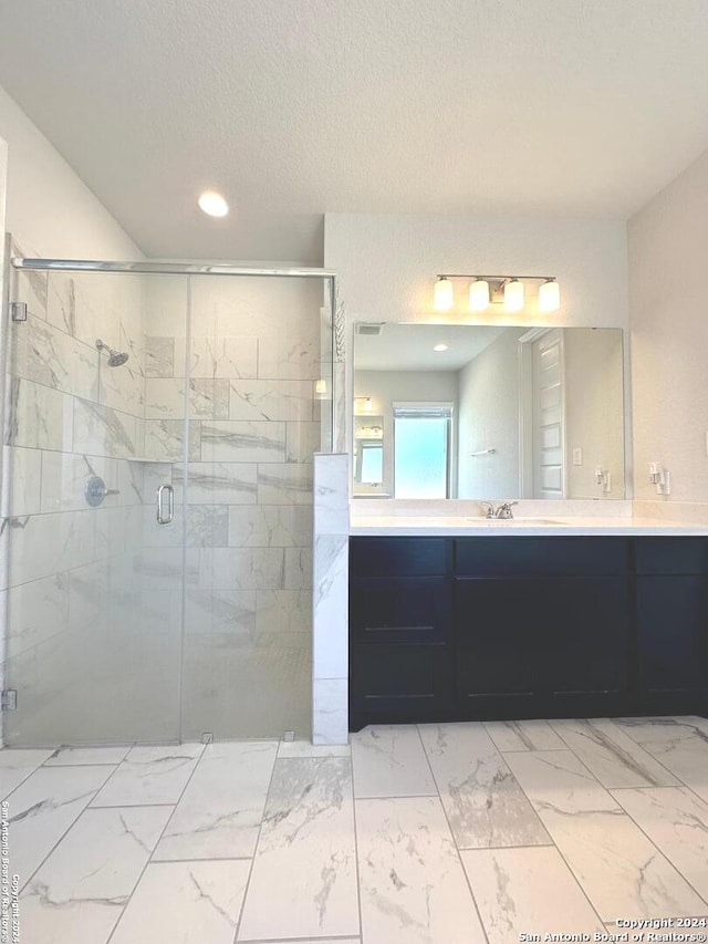 bathroom with vanity, a shower with shower door, and a textured ceiling