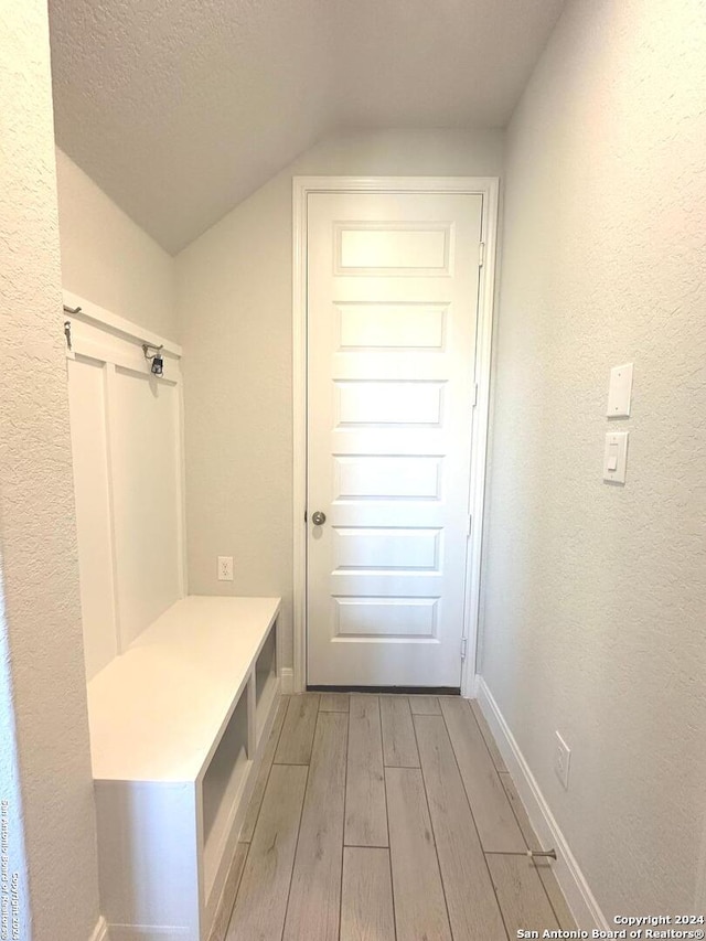 mudroom featuring vaulted ceiling, a textured ceiling, and light hardwood / wood-style flooring