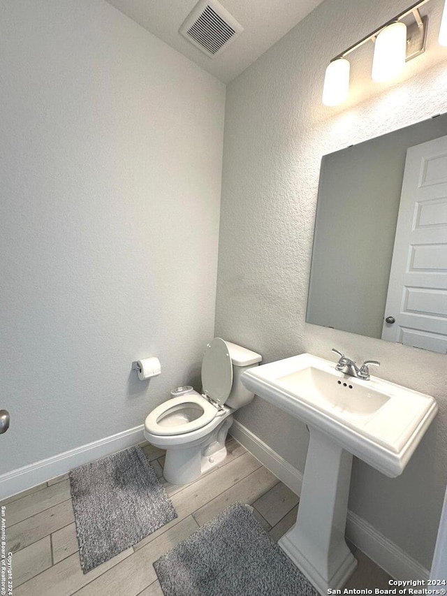 bathroom featuring toilet, wood-type flooring, and sink