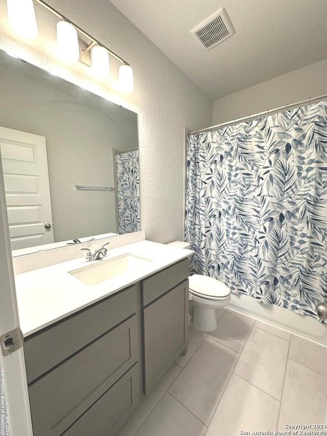 full bathroom featuring tile patterned flooring, vanity, toilet, and shower / tub combo with curtain