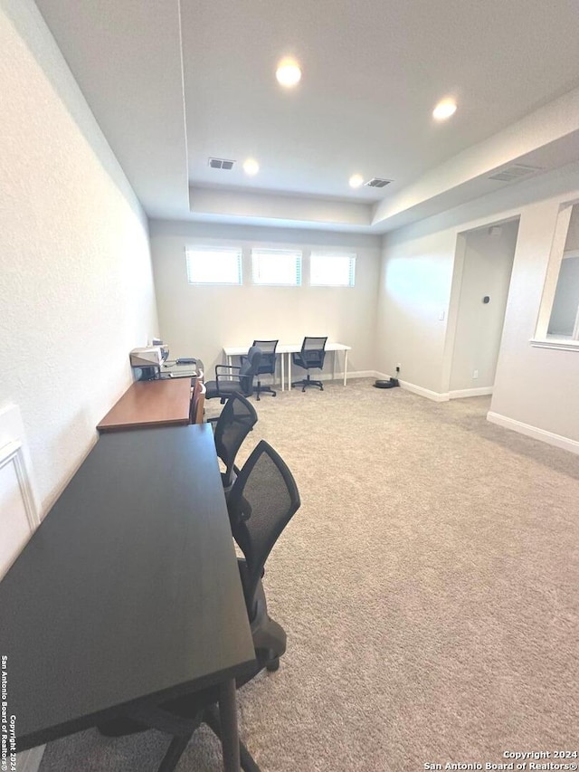 carpeted home office with a tray ceiling