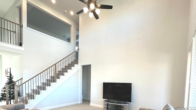 staircase with hardwood / wood-style floors, a towering ceiling, and ceiling fan