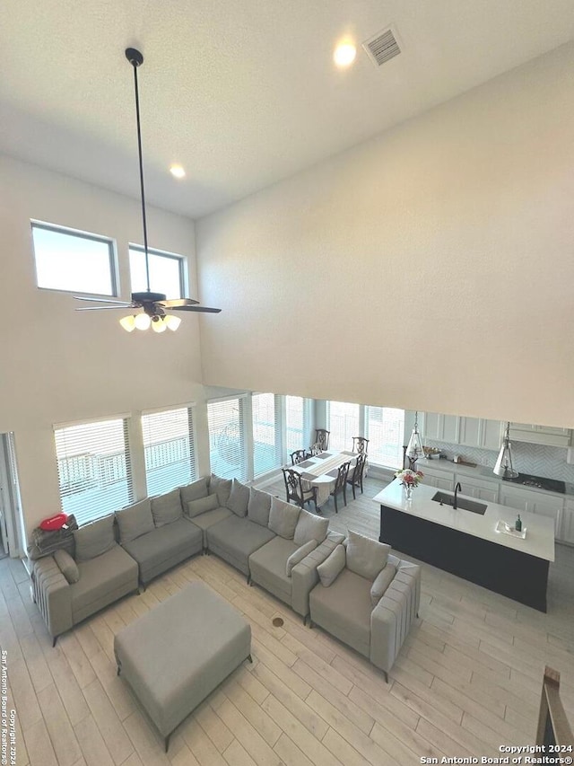 living room with light wood-type flooring, a high ceiling, and a wealth of natural light