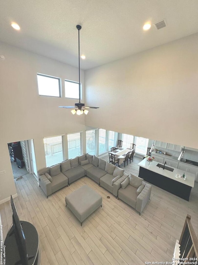 living room featuring light hardwood / wood-style flooring, ceiling fan, and a healthy amount of sunlight