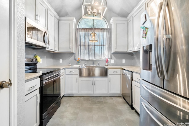 kitchen with white cabinets, decorative light fixtures, lofted ceiling, and appliances with stainless steel finishes