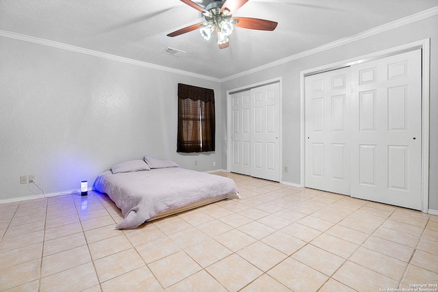 tiled bedroom featuring a textured ceiling, multiple closets, ceiling fan, and crown molding