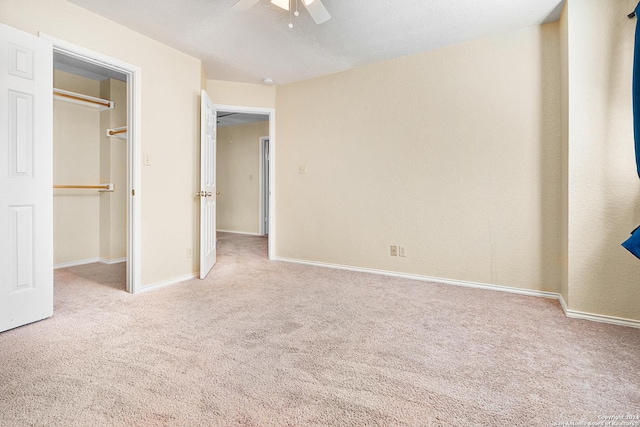 unfurnished bedroom featuring ceiling fan, light colored carpet, and a closet