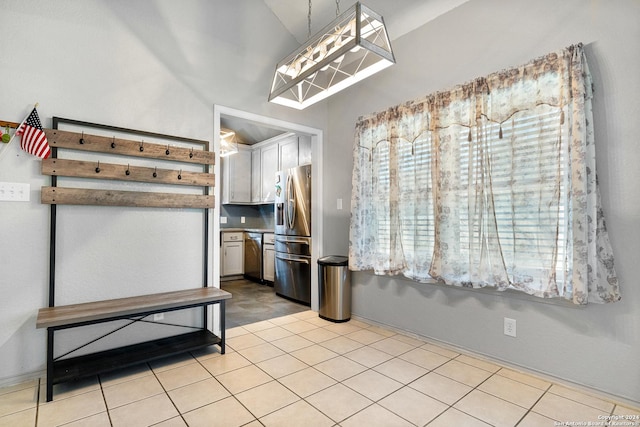 kitchen featuring hanging light fixtures, vaulted ceiling, light tile patterned floors, white cabinetry, and stainless steel appliances