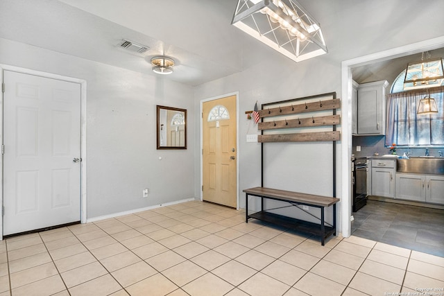 kitchen featuring black range, light tile patterned floors, sink, and hanging light fixtures