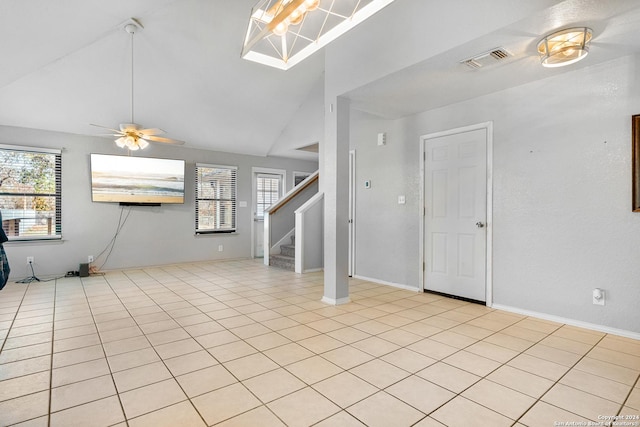 unfurnished living room with ceiling fan, light tile patterned floors, and vaulted ceiling