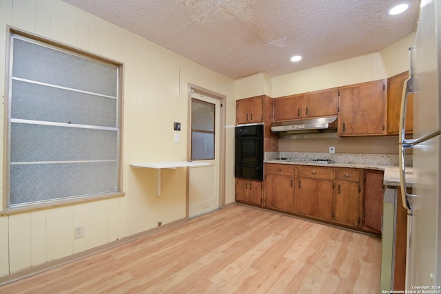 kitchen with a textured ceiling, stainless steel appliances, and light hardwood / wood-style floors