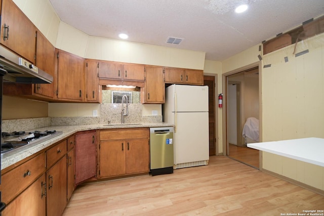 kitchen featuring sink, light wood-type flooring, a textured ceiling, and appliances with stainless steel finishes