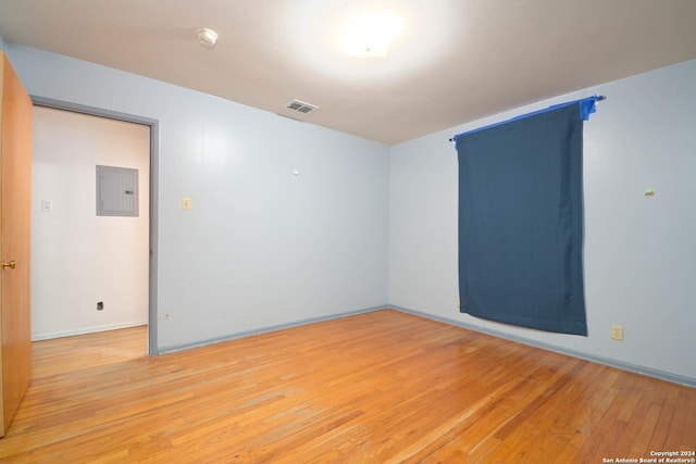 spare room with electric panel and light hardwood / wood-style flooring