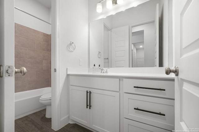 full bathroom with hardwood / wood-style floors, vanity, tiled shower / bath combo, and toilet