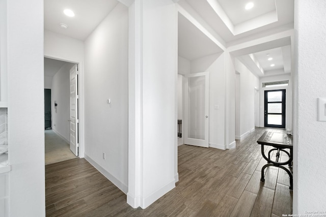 hall with wood-type flooring, a tray ceiling, and french doors