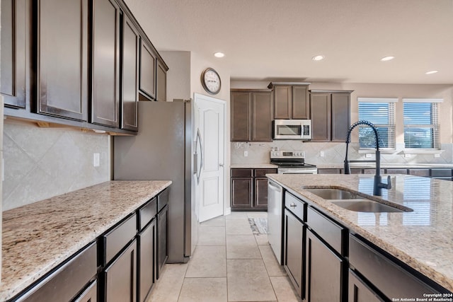 kitchen featuring light stone countertops, dark brown cabinetry, stainless steel appliances, and sink