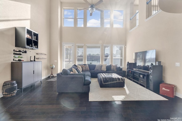 living room with ceiling fan, dark hardwood / wood-style flooring, and a high ceiling