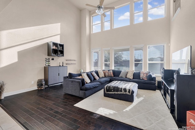 living room with a towering ceiling, hardwood / wood-style flooring, and ceiling fan