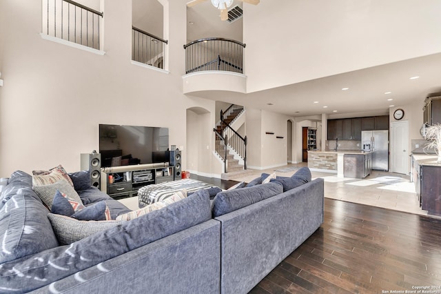 living room featuring ceiling fan, dark hardwood / wood-style flooring, and a towering ceiling