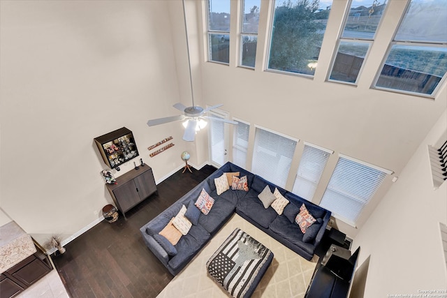 living room with ceiling fan, hardwood / wood-style floors, and a towering ceiling