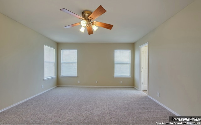 empty room featuring a wealth of natural light, ceiling fan, and light colored carpet