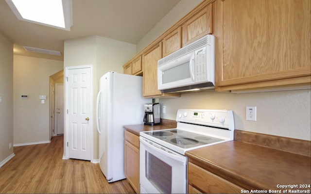 kitchen with light brown cabinets, white appliances, and light hardwood / wood-style flooring