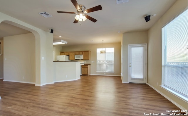 unfurnished living room featuring wood-type flooring, plenty of natural light, and ceiling fan