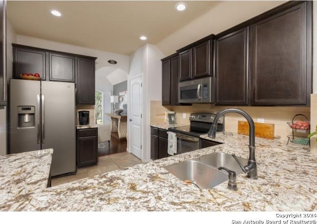 kitchen featuring dark brown cabinetry, light stone countertops, sink, and stainless steel appliances