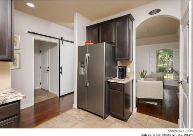 kitchen featuring dark brown cabinetry, stainless steel fridge with ice dispenser, and light hardwood / wood-style floors