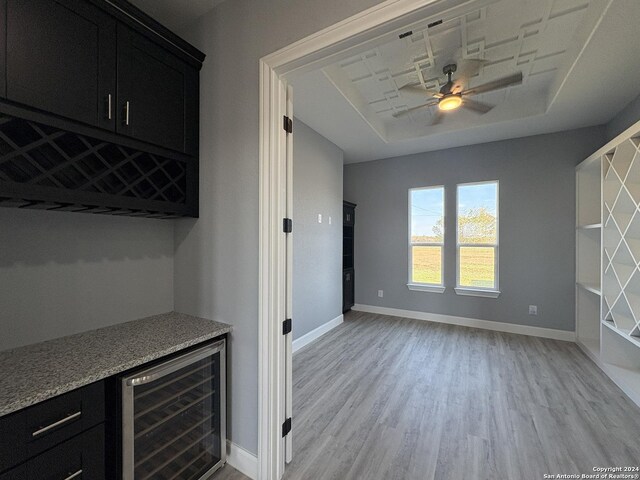 interior space featuring light stone countertops, ceiling fan, light hardwood / wood-style flooring, and beverage cooler