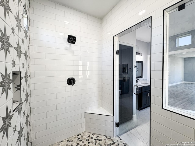 bathroom with a tile shower, vanity, and tile walls