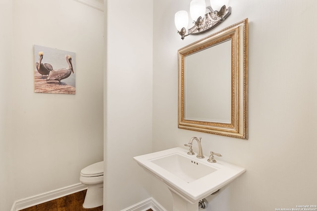 bathroom featuring wood-type flooring, toilet, and sink