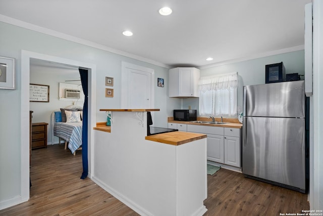 kitchen with wooden counters, white cabinetry, stainless steel refrigerator, and dark wood-type flooring
