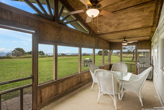 sunroom featuring a healthy amount of sunlight, ceiling fan, a rural view, and lofted ceiling