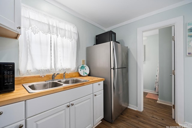kitchen with butcher block countertops, stainless steel fridge, white cabinetry, and sink
