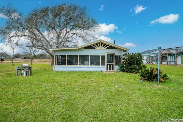 rear view of house featuring a lawn and a sunroom