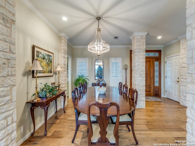 dining space with a notable chandelier, ornate columns, crown molding, and light hardwood / wood-style flooring