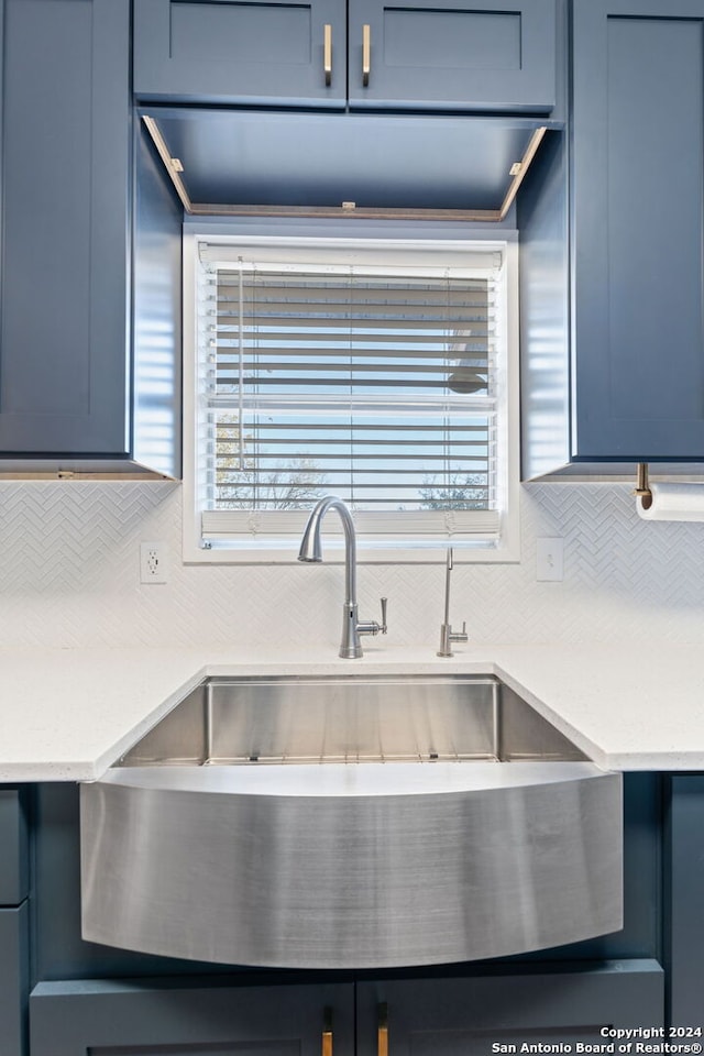 kitchen with backsplash, blue cabinets, and sink