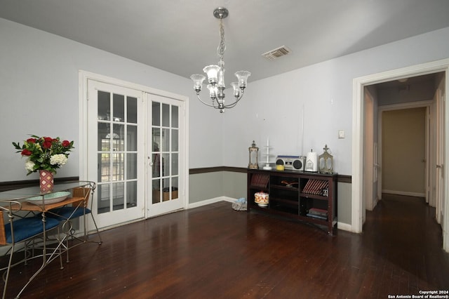 dining area with dark wood-type flooring and an inviting chandelier