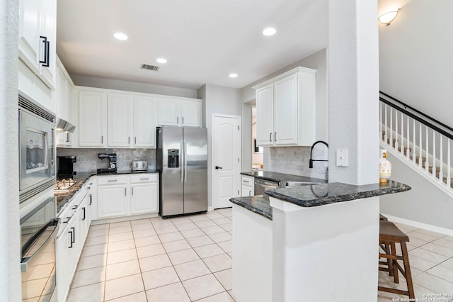 kitchen with white cabinets, a kitchen breakfast bar, appliances with stainless steel finishes, tasteful backsplash, and kitchen peninsula