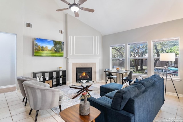 tiled living room with a tile fireplace, ceiling fan, and high vaulted ceiling