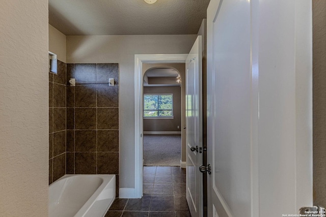 bathroom featuring a textured ceiling, tile patterned floors, and tiled shower / bath