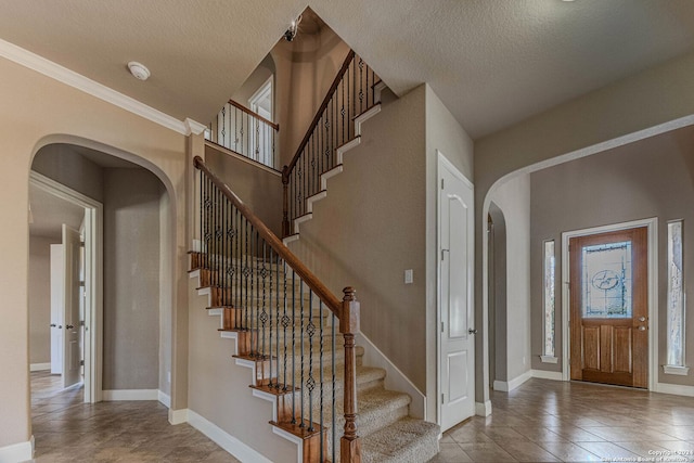 tiled foyer entrance featuring crown molding and a textured ceiling