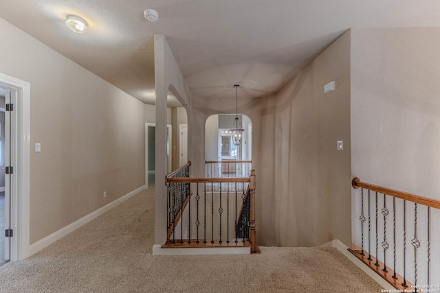 hall with carpet and an inviting chandelier