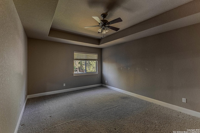 unfurnished room featuring carpet flooring, a textured ceiling, a raised ceiling, and ceiling fan