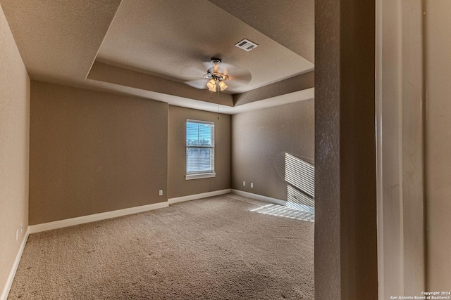 unfurnished room featuring carpet flooring, a textured ceiling, a raised ceiling, and ceiling fan