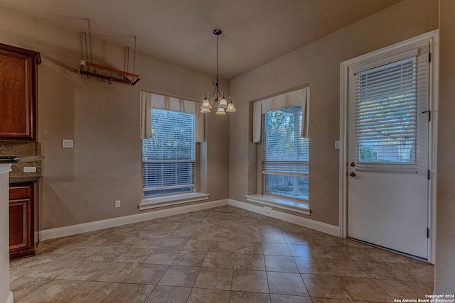 unfurnished dining area with light tile patterned floors, an inviting chandelier, and a wealth of natural light