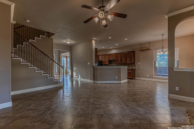 unfurnished living room featuring a textured ceiling, plenty of natural light, and ceiling fan with notable chandelier