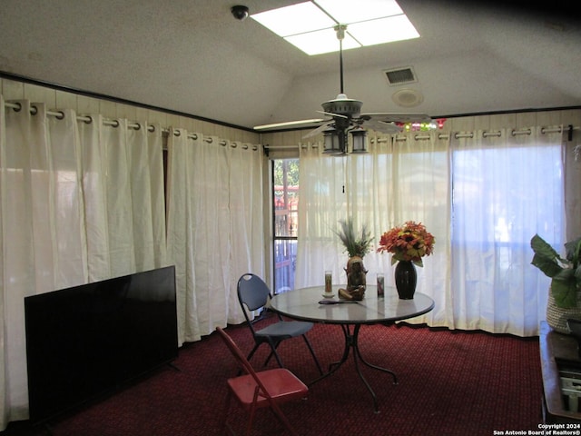 carpeted dining area with ceiling fan and lofted ceiling